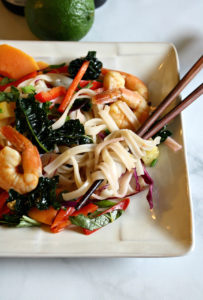 Plate with chopsticks in rice noodle salad with veggies and shrimp