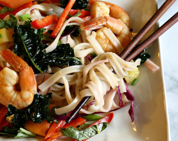 Plate with chopsticks in rice noodle salad with veggies and shrimp