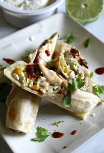 Plate with chicken and corn filled tortillas with lime, sriracha, dairy free cream cheese