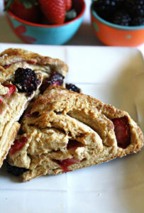 White plate with 2 dairy free scones with fresh strawberries and blackberries