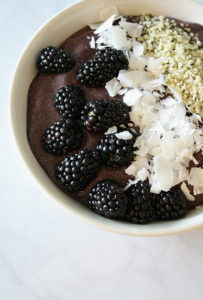 White bowl filled with Blueberry Superfood Smoothie Bowl topped with blackberries, coconut chips, and hemp hearts