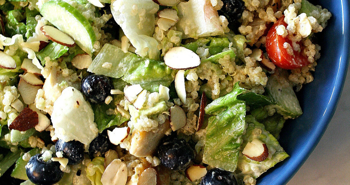 Bowl filled with dairy free salad including romaine lettuce, quinoa, blueberries, chicken, and almonds