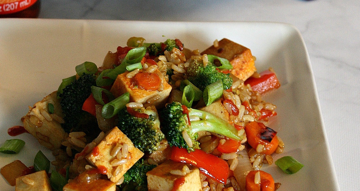 White plate on marble surface with stir fry vegetables and tofu