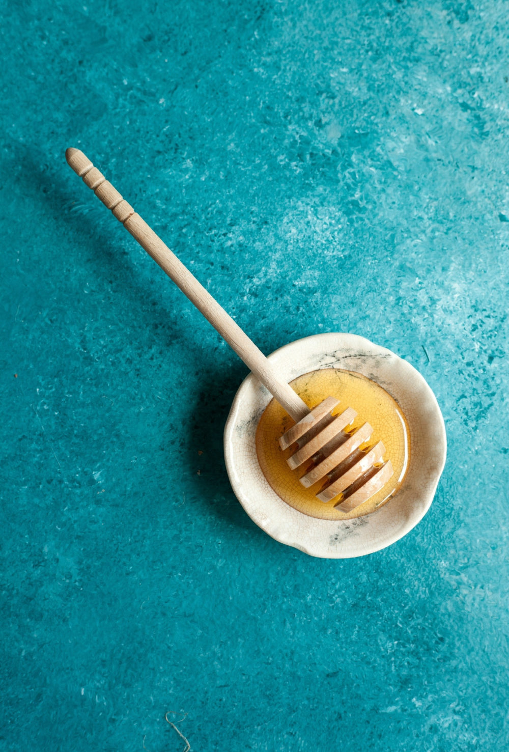 Bowl of honey with teal background