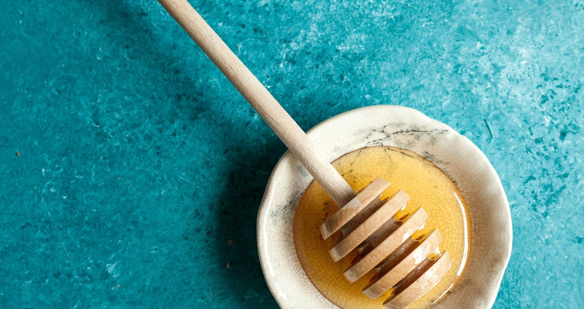 Bowl of honey with teal background