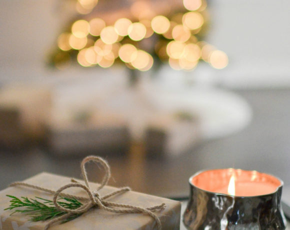 gift sitting on glass table with candle and Christmas tree